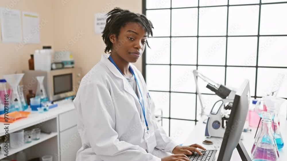 A young african american woman with dreadlocks, wearing a lab coat and ...