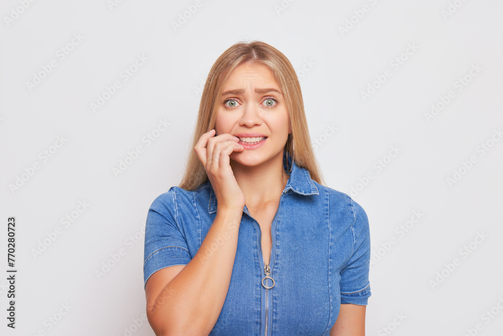 A woman in an electric blue shirt nervously bites her nails A woman in an electric blue shirt nervously bites her nails