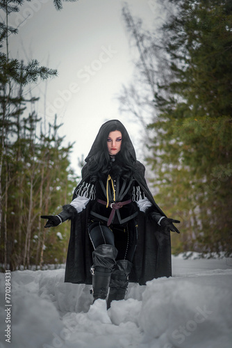 Beautiful young enchantress walking in the winter forest. photo