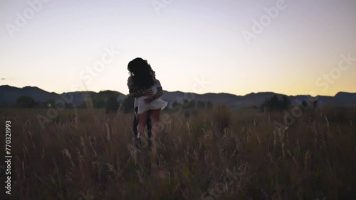 Lovers run around and kiss in a field during sunset photo