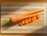 A carrot with its rich orange hue, cut into thin sticks, arranged neatly on a bamboo cutting board, showcasing its crisp texture.