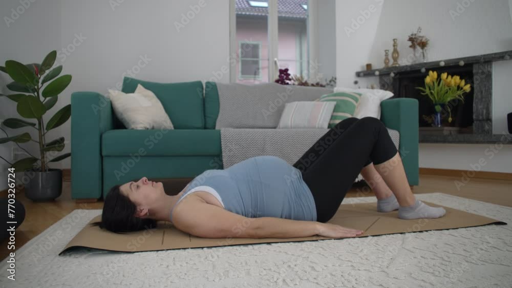 Pregnant woman doing pilates exercises at home living room by herself. 30s lady taking care of lower back by practicing sport during late stage pregnancy Pregnant woman doing pilates exercises at home living room by herself. 30s lady taking care of lower back by practicing sport during late stage pregnancy