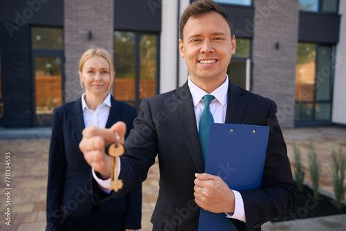 Realtor holding keys in hand while standing near client woman