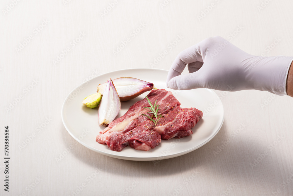 Sprinkling salt on beef on a white plate