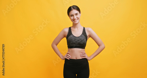 Portrait of a young woman wearing sportswear. Isolated on yellow background in studio. © ronnarong