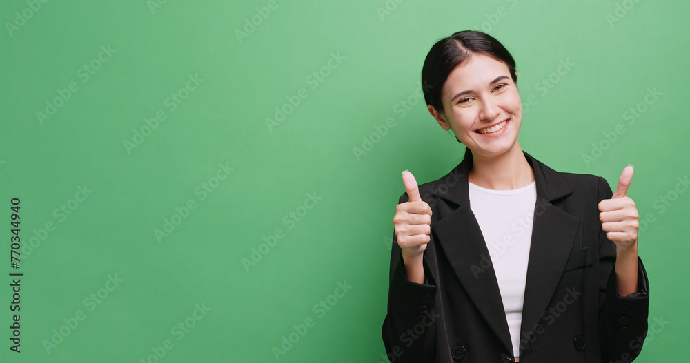 Young businesswoman is showing approval for something. Isolated on green background in studio. Young businesswoman is showing approval for something. Isolated on green background in studio.