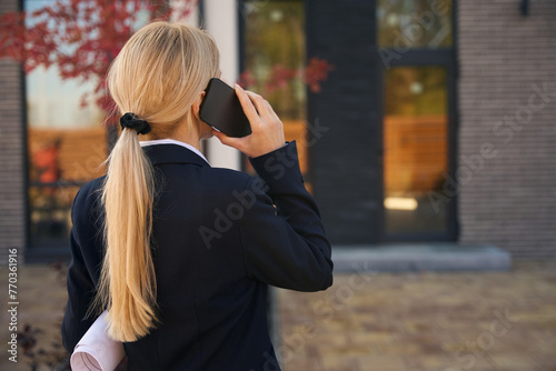 Back view picture of businesswoman standing and talking on phone