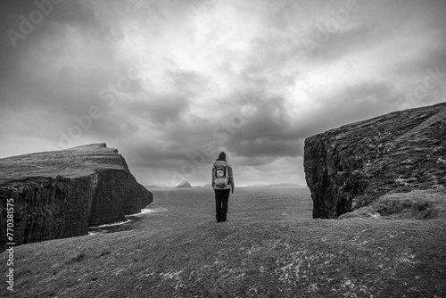 Black and white image of woman standing alone at edge of cliff. photo