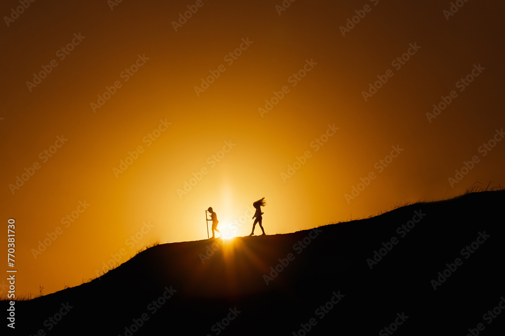 Two kids walking down hill in sunset Two kids walking down hill in sunset