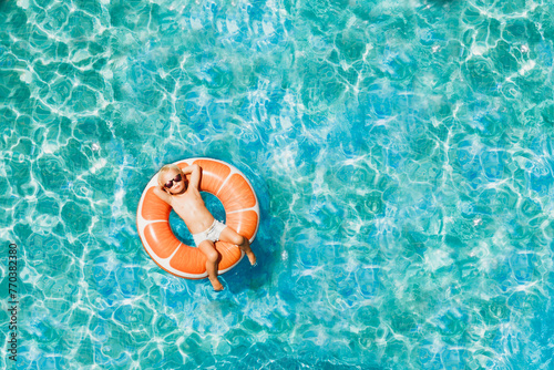 Boy has fun on family vacation rest in pool with donut ring