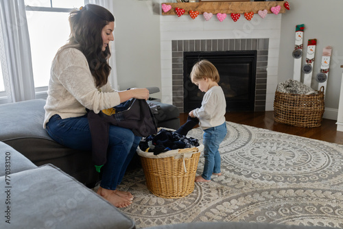 Woman folds laundry while her daughter tries to help photo
