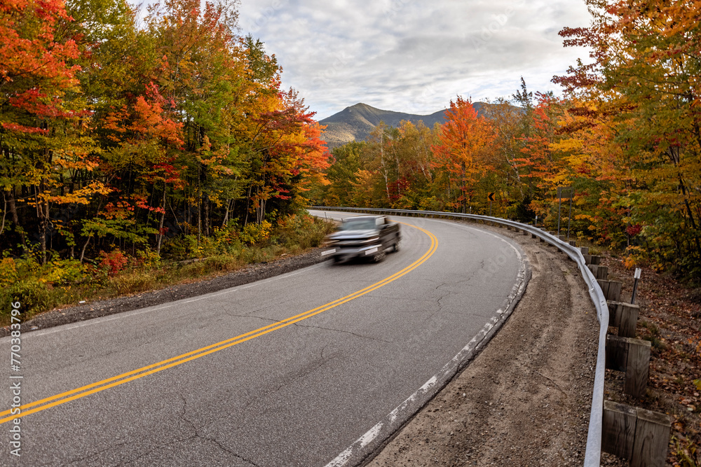 Speeding vehicle with curvy mountain road and vibrant autumn leaves Speeding vehicle with curvy mountain road and vibrant autumn leaves