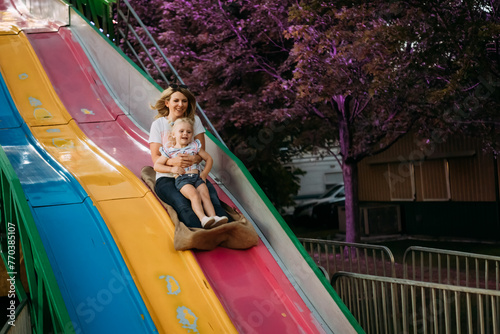 Mom and daughter sliding down fun slide at carnival photo