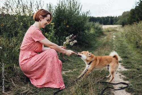 A girl plays with a dog in nature in the summer