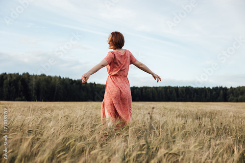 Girl dancing in the field on a summer day photo