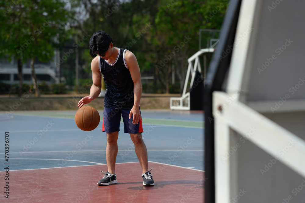 Basketball player bouncing the ball in an urban court. Sport and active lifestyle concept