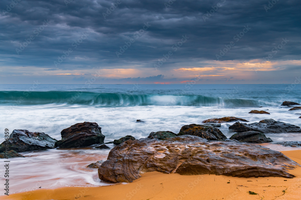 Sunrise at the seaside with rocks and beautiful diffused light by the rain clouds Sunrise at the seaside with rocks and beautiful diffused light by the rain clouds