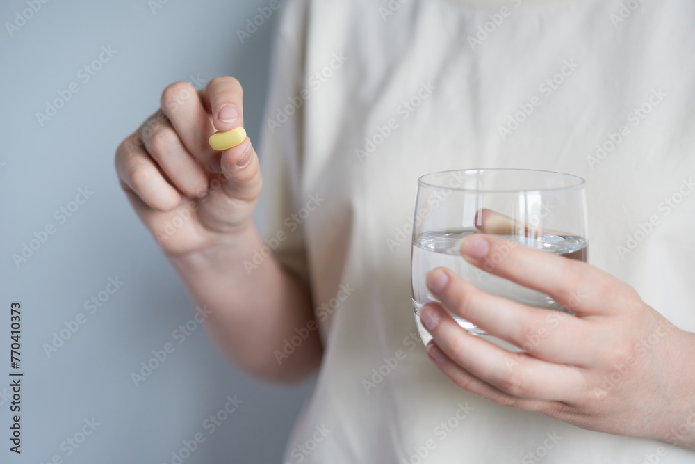 Close-up of female hands holding a pill and a glass of water Close-up of female hands holding a pill and a glass of water