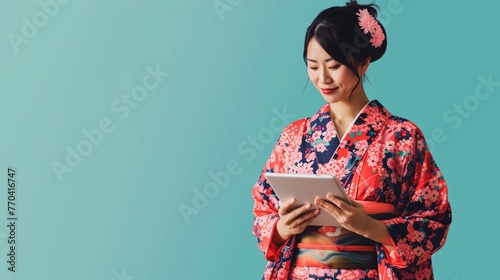 Japanese female using tablet device on solid background.