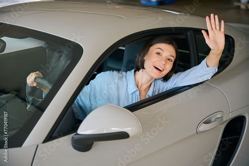 Business lady greeting, driving automobile at parking