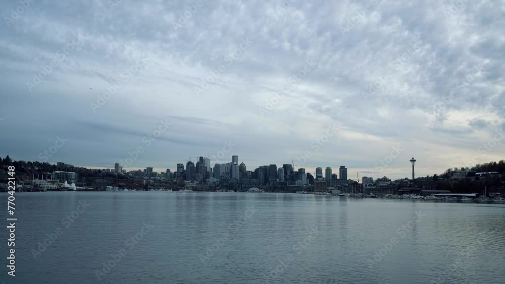 Tilt down shot revealing the Seattle city skyline with skyscrapers, the sky needle and Lake Union with a sail boat from the famous tourist destination, Gas Works Park on a cold overcast spring evening Tilt down shot revealing the Seattle city skyline with skyscrapers, the sky needle and Lake Union with a sail boat from the famous tourist destination, Gas Works Park on a cold overcast spring evening