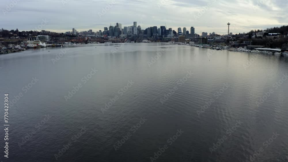 Tilt up dolly in aerial drone shot revealing the Seattle city skyline with skyscrapers, the space needle and Lake Union from the famous tourist destination, Gas Works Park on overcast spring evening