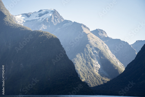 Fjord landscape with lush forest and high peak with glacier towering above the sea, New Zealand