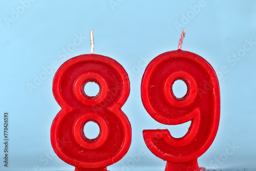 close up on a red number eighty ninth birthday candle on a white background.
 photo