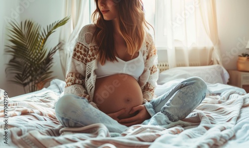 Pregnant woman with visible belly sitting on bed