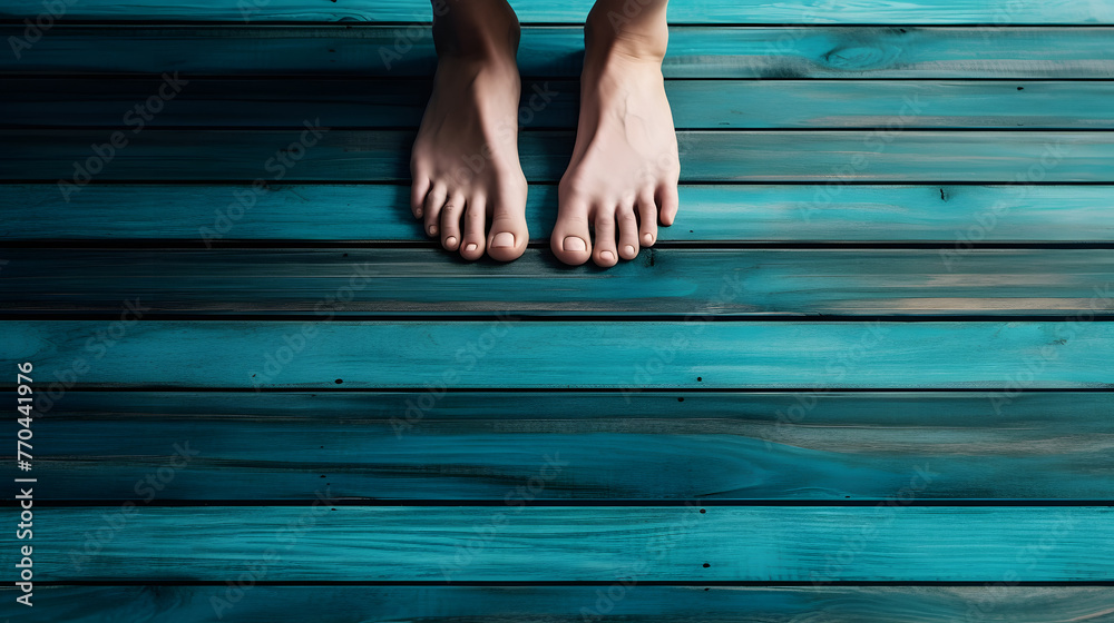 woman's feet with white nail polish on her toes, standing barefoot in the middle of an old blue wooden floor