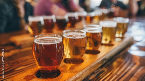 A row of assorted beers in a tasting flight, displayed on a wooden table at a bustling brewery.