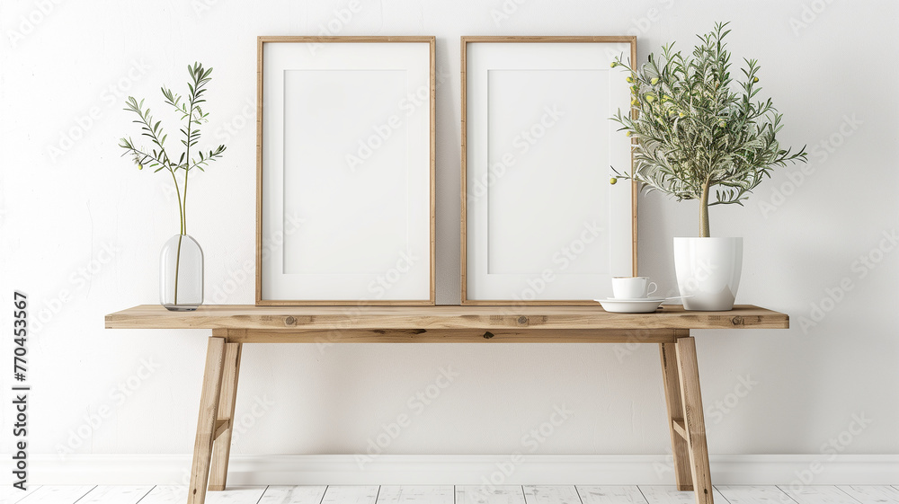 A wooden table with two white poster frames on it, olive tree in the pot near wall. Scandinavian home interior design of modern entrance hall or hallway. A wooden table with two white poster frames on it, olive tree in the pot near wall. Scandinavian home interior design of modern entrance hall or hallway.