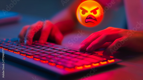 Hand typing on keyboard with an angry emoji face symbol, conveying anger and rage against a red glowing light effect background.