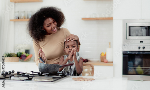 Multiracial mother and son have fun cooking food together in kitchen at home. Young multiethnic woman and her little child preparing healthy lunch with fresh vegetable. Motherhood enjoyment lifestyle.