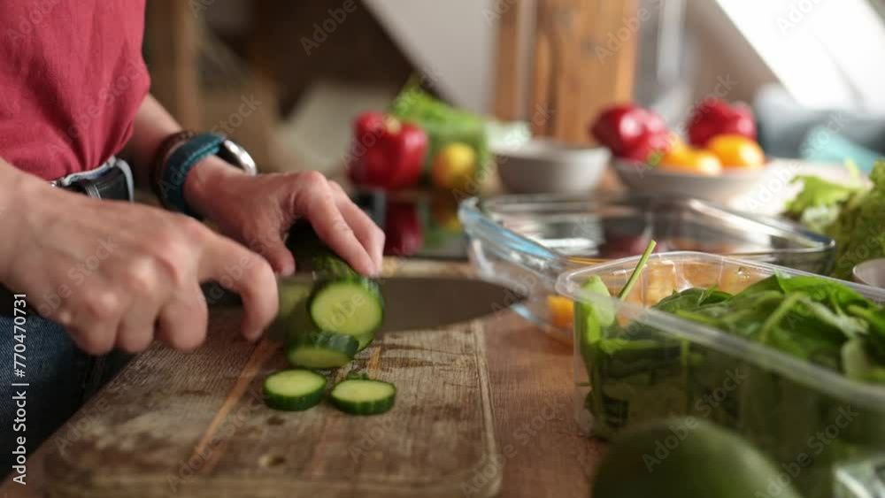 girl cutting a cucumber on a cutting board in the kitchen for the healthy vegetable salad girl cutting a cucumber on a cutting board in the kitchen for the healthy vegetable salad
