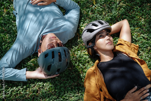 A young couple laying down the grass during their bike ride.