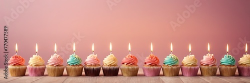 Colorful cupcakes with lit candles are displayed against a pink background, indicating an indoor celebration event marking of joy and celebrating. with free space