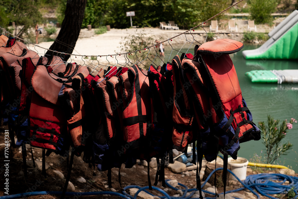 Fototapeta premium Life jackets hanging against the backdrop of the sea. For sale: lifesaving equipment for marine excursions and tours, emphasizing safety on cruises and yacht outings. Marine services and training.
