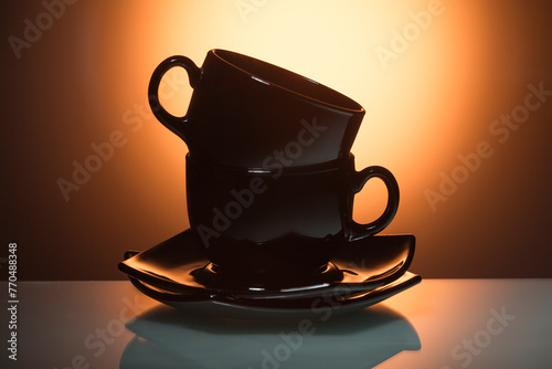 Set of Two Glassed Teacups With Plate isolated Over Glowing Orange Gradient Background.