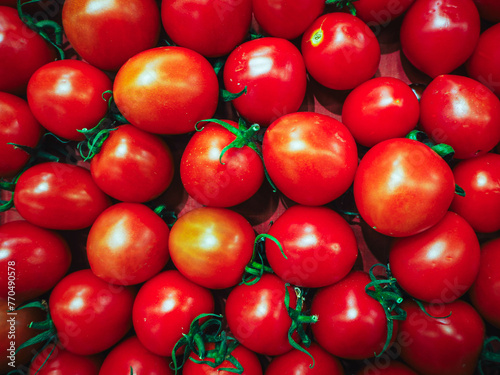 many fresh tomatoes with sprigs, leaves on the shelf of supermarket. © Elisaveta