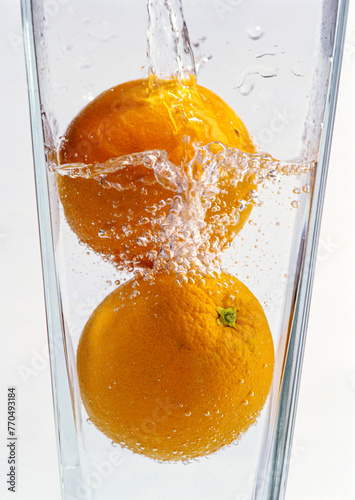 Fresh orange in clear water glass