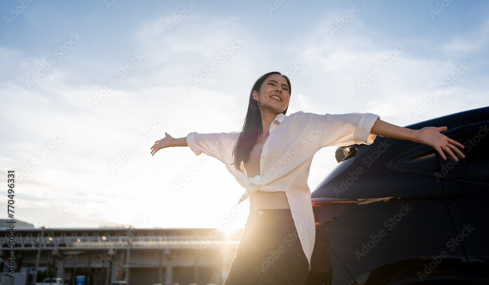 Young beautiful asian women buying new car. she was standing near car on the roadside. Beautiful moment blue sky Smiling female driving travel by vehicle on the road on a bright day with sun light. - obrazy, fototapety, plakaty 