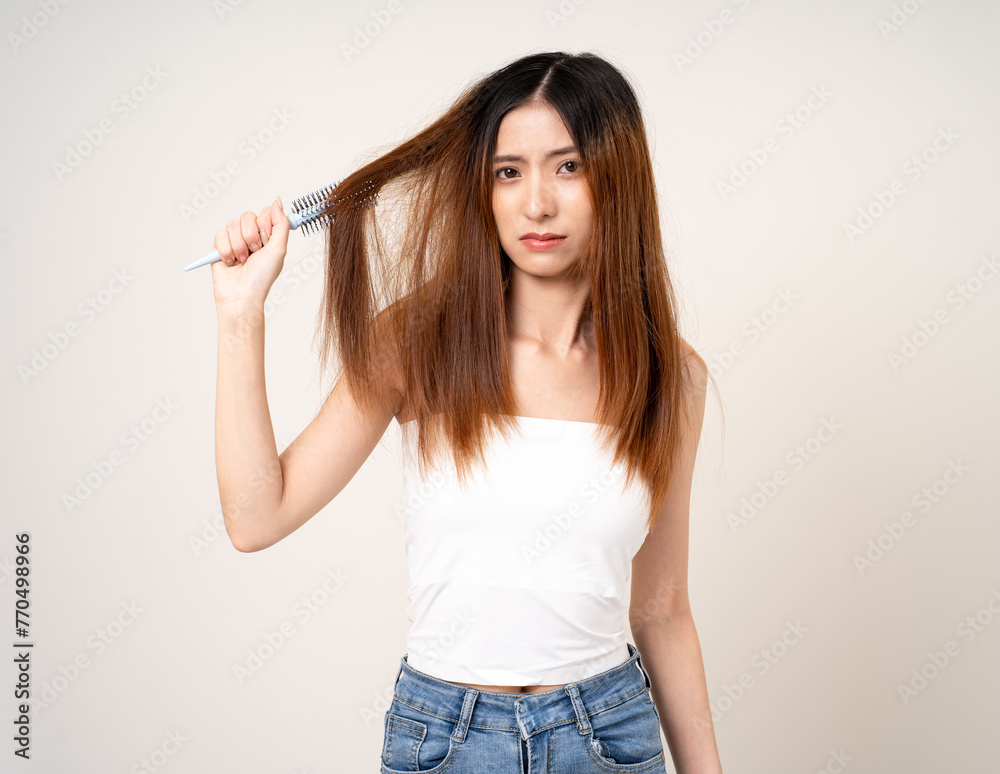 Young asian woman having problems with her hair Thin damaged dry hair falls out easily and is not healthy have to cut off. Standing on isolated white background Young asian woman having problems with her hair Thin damaged dry hair falls out easily and is not healthy have to cut off. Standing on isolated white background