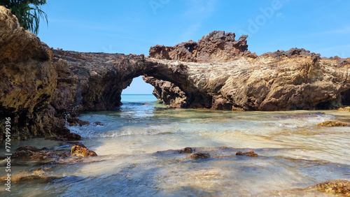 A rocky beach with a small arch standing in the middle, framing the scenic view of the surrounding seascape
