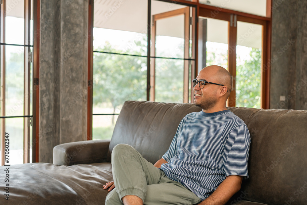 Handsome asian man sitting rest on sofa couch in living room at home. Happy Portrait of cheerful smiling asian man relax in the house. People quality time and successful in life