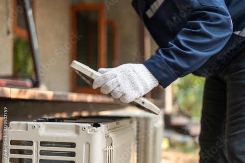 Air conditioner service outdoor checking fix repair. Air conditioner cleaning technician He opened the front cover and took out the filters and washed it. He in uniform wearing rubber