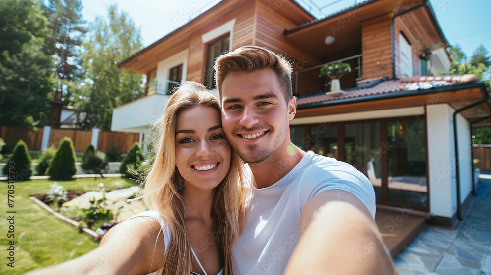 A young married couple takes a selfie against the background of a purchased private house