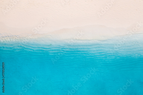 Summer seascape beautiful waves, blue sea water in sunny day. Top view from drone. Sea aerial view, amazing tropical nature background. Beautiful bright sea with waves splashing and beach sand concept