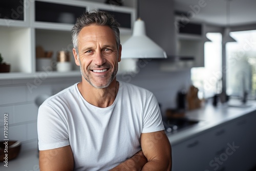 Handsome middle-aged man smiles in kitchen home, modern kitchen background, natural lighting © Slanapotam