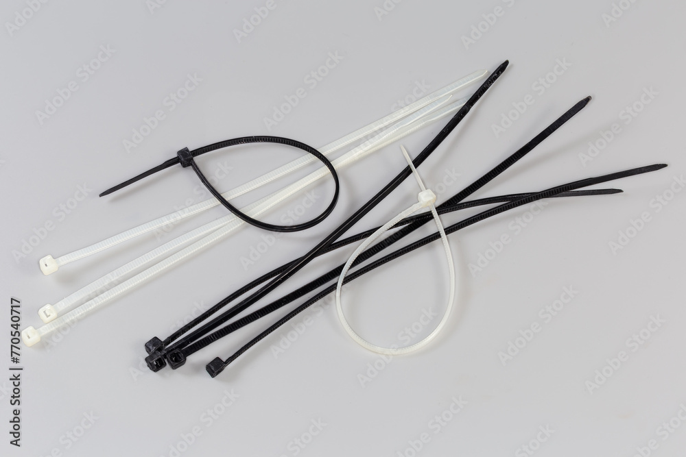 Black and white nylon unfastened cable ties on gray background - obrazy, fototapety, plakaty 